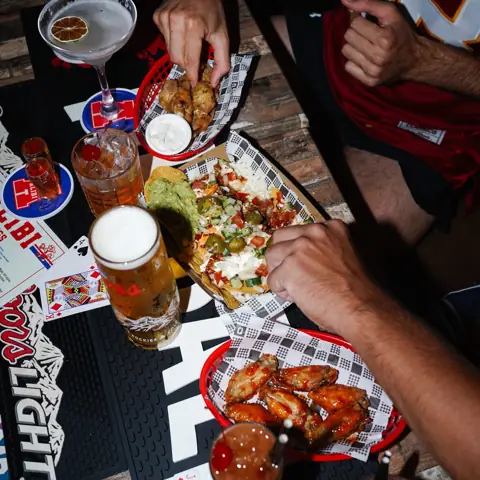 Table loaded with wings, nachos and drinks